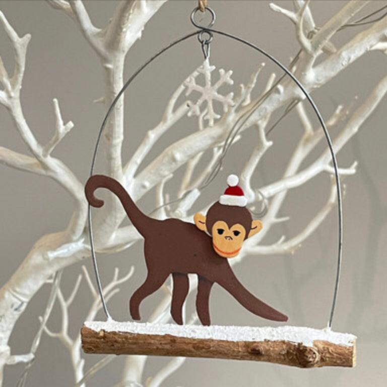 Monkey walking on branch hanging Christmas decoration