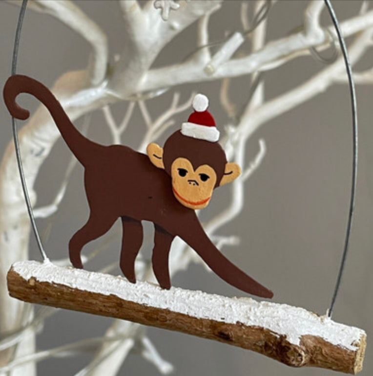 Monkey walking on branch hanging Christmas decoration