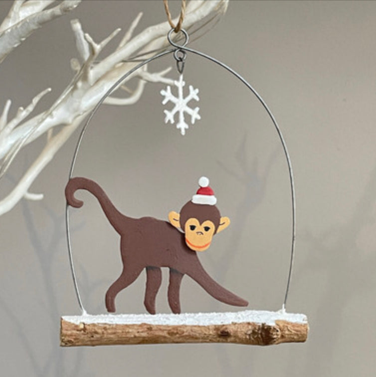 Monkey walking on branch hanging Christmas decoration